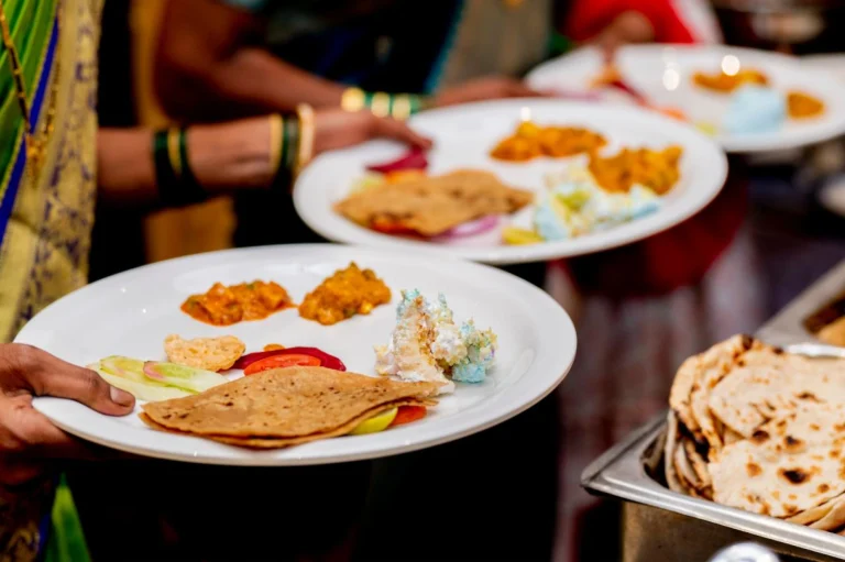 A guest plate filled with hot puris, vegetable subzi, aromatic pulav, and fresh salad