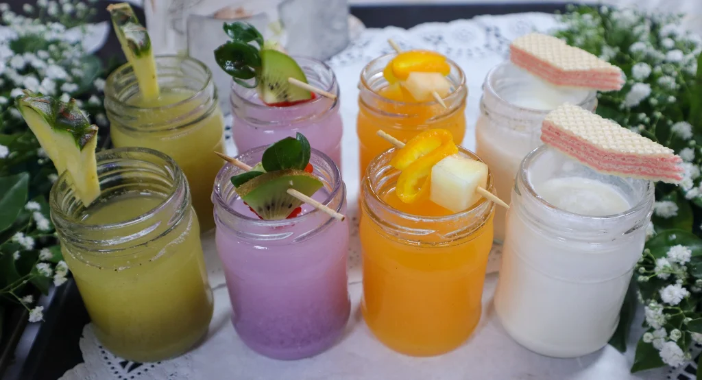 Colorful welcome drinks in jars including fruit juices, milkshakes, and mocktails garnished with fresh fruits