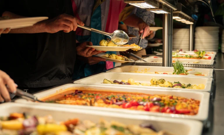 Guests serving food from a buffet counter at a professionally managed catering event