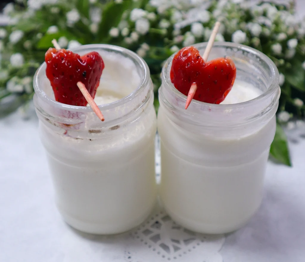 Strawberry milk drink served in glass jars with heart-shaped strawberry garnish for welcome drink