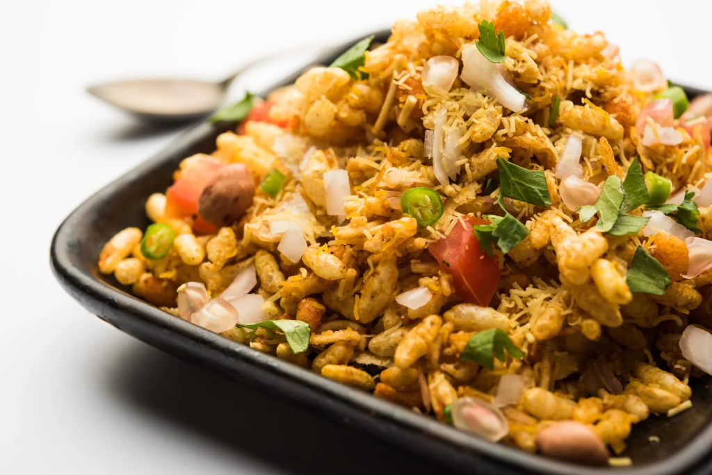 Bhel puri Indian chaat made with puffed rice, sev, peanuts, onions, tomatoes, and chutneys in a bowl