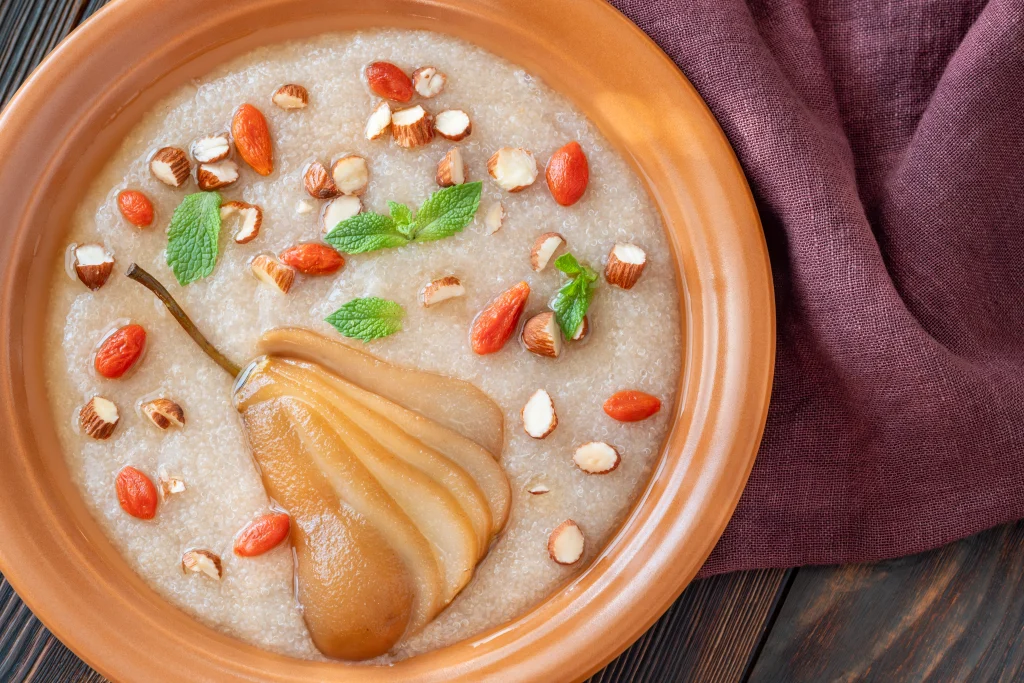 Kezhvaragu Koozh (millet porridge) elevated with modern toppings like poached pear, almonds, and goji berries
