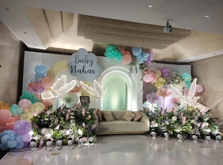 Baby shower stage decor with pastel balloons and floral arrangements for a celebration catered by Sar V Sri