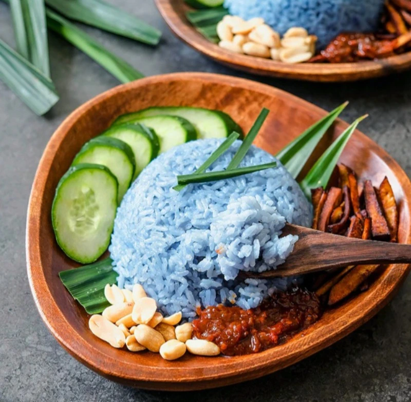 Burmese blue rice served with cucumber slices, peanuts, fried shallots, and sambal by burmese food catering