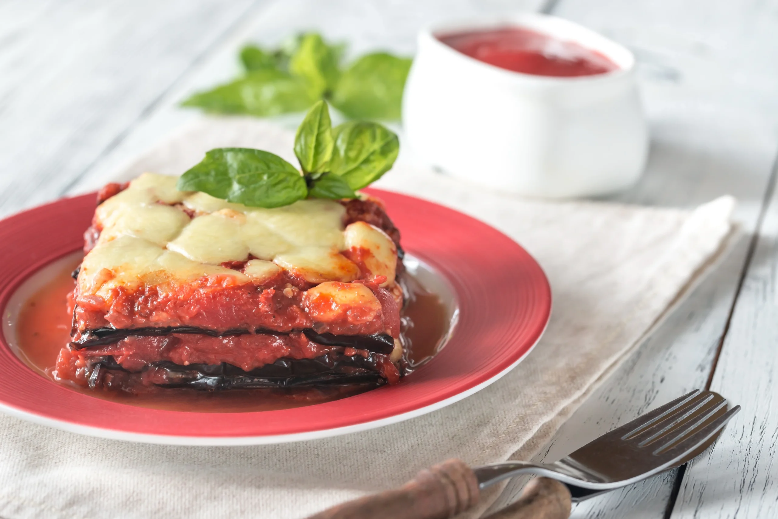 Delicious vegetable lasagna with layers of eggplant, mozzarella cheese, and tomato sauce, garnished with fresh basil