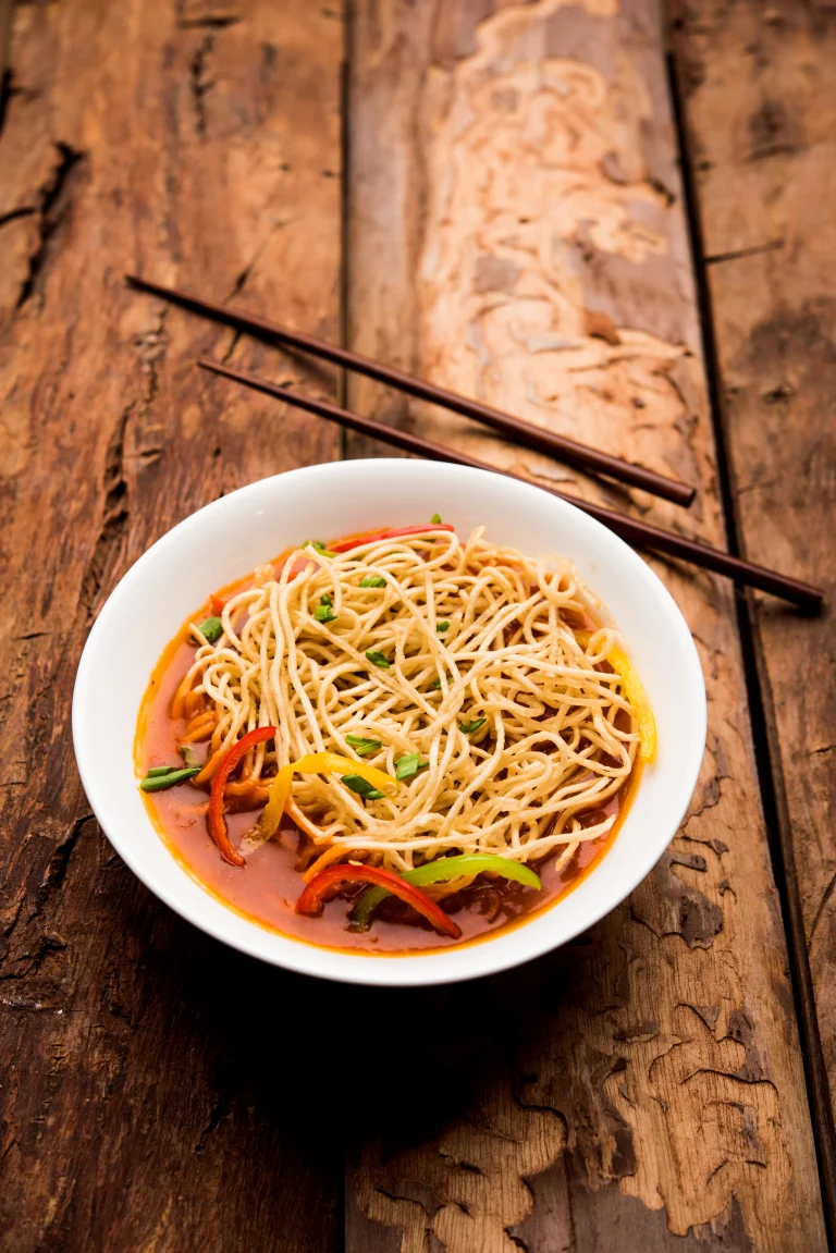 Traditional Burmese Khow Suey with noodles, vegetables, and garnishes in a flavorful broth.