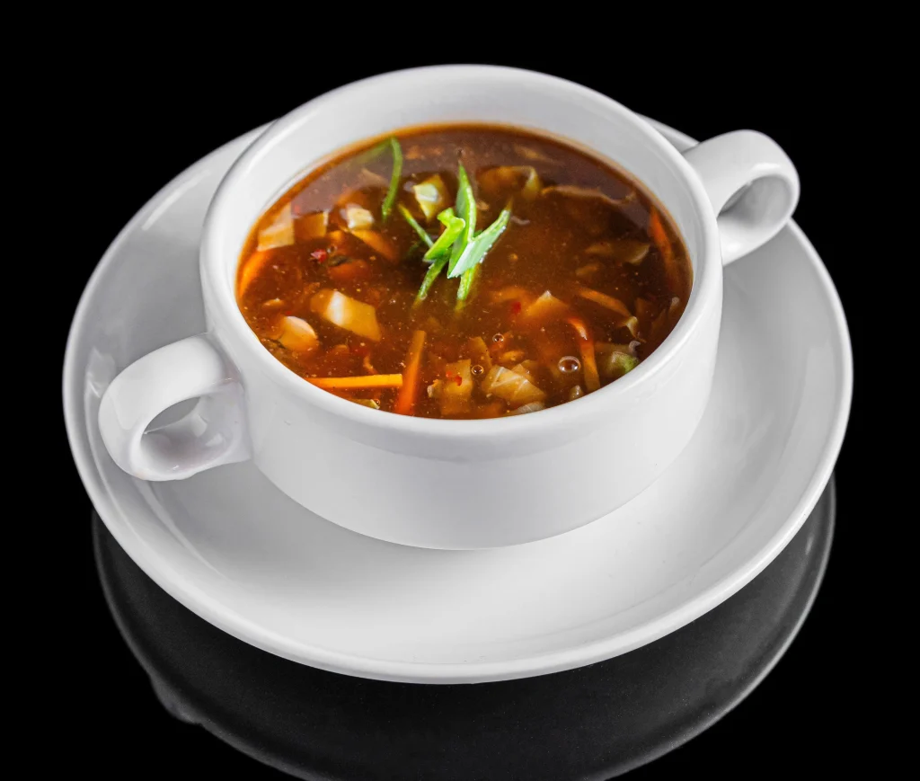 Authentic Indo-Chinese Hot and Sour Vegetable Soup served in a white ceramic soup bowl