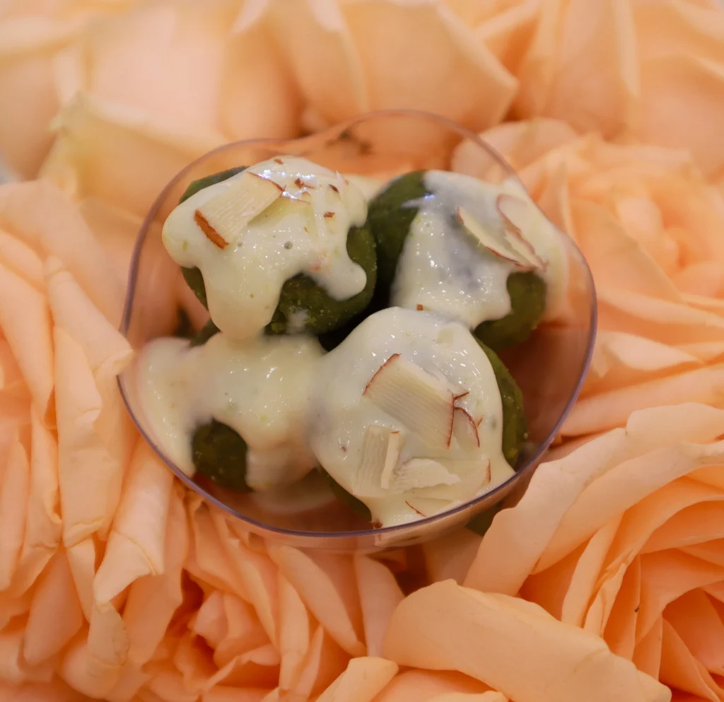 Jain sweet dish made with pistachio, garnished with saffron and almonds, served by a Sar V Sri Jain Catering Services