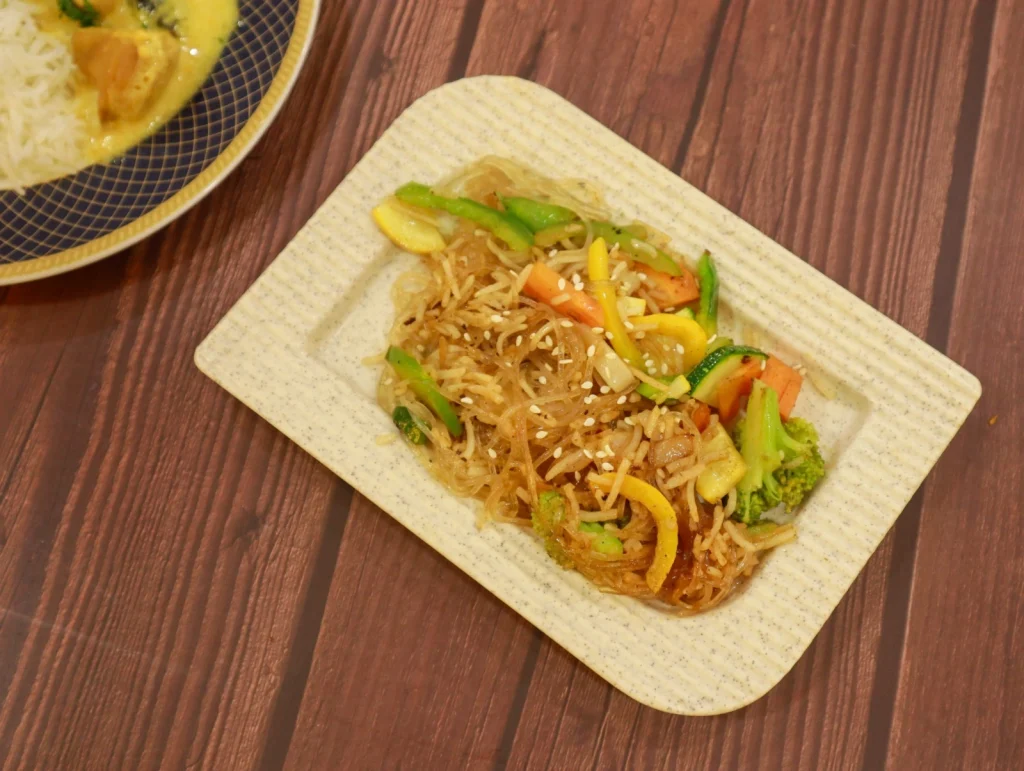 Pan Asian vegetable noodles stir-fried with bell peppers, broccoli, and sesame seeds served on a plate