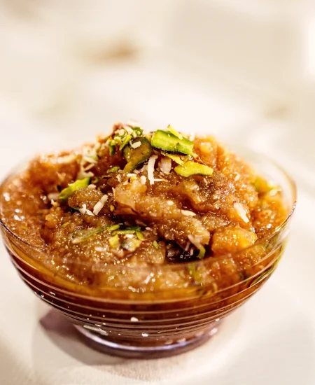 Andhra style sweet dessert served in a glass bowl, garnished with chopped nuts and pistachios.