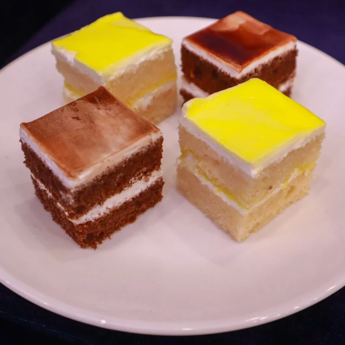 Baby Shower Catering Services Close-up of cake slices with yellow and brown icing on a white plate