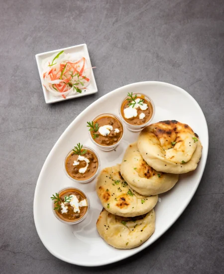Jain Dal Makhani served with freshly baked naan, accompanied by salad, in small cups