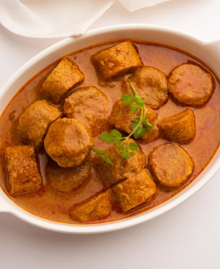 Jain Gatte Ki Sabzi – Traditional gram flour dumplings in a rich, spiced curry, garnished with coriander leaves